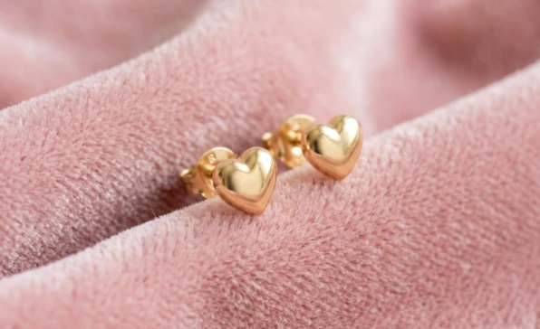 Aretes de corazón en oro sobre terciopelo rosa